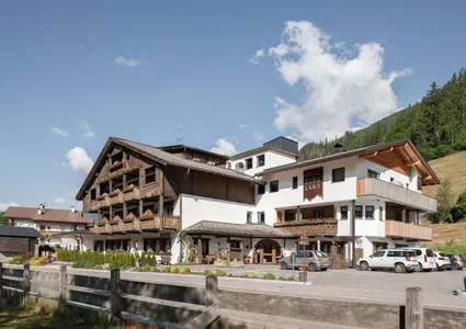 Hotel Bergland Ahrntal im Sommer mit bewaldeten Bergen im Hintergrund