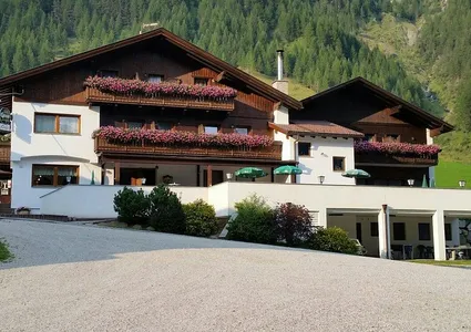 Traditioneller Südtiroler Gasthof mit Blumenbalkonen vor bewaldetem Bergpanorama im Ahrntal im Sommer