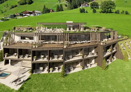 Modernes Hotel in Holzbauweise mit begrünten Terrassen, eingebettet in die grüne Wiesenlandschaft des Ahrntals