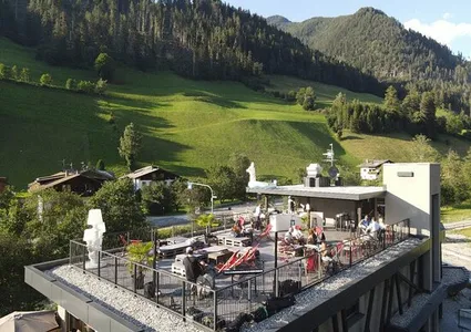 Moderne Dachterrasse mit Liegestühlen und Blick auf Alpenwiesen im Sommer