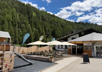 Sonnige Außenterrasse mit Sonnenschirmen und Hütte am Fuße des Bergs im Ahrntal