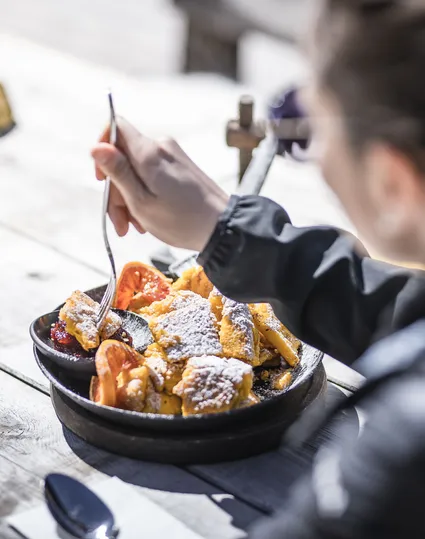 Kaiserschmarrn in der Pfanne auf rustikalem Holztisch einer Skihütte im Ahrntal