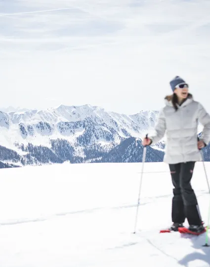 Paar beim Schneeschuhwandern auf sonniger Hochebene im Ahrntal mit Bergpanorama Südtirols