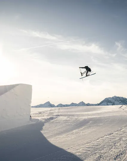 Freestyle-Skifahrer beim Grab-Trick im Snowpark Klausberg im goldenen Abendlicht