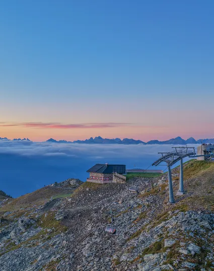 Bergstation mit Sessellift am Klausberg bei Sonnenuntergang über dem Wolkenmeer und Dolomitenpanorama