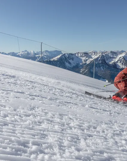 Skifahrer im roten Anzug beim Carving auf perfekt präparierter Piste am Klausberg