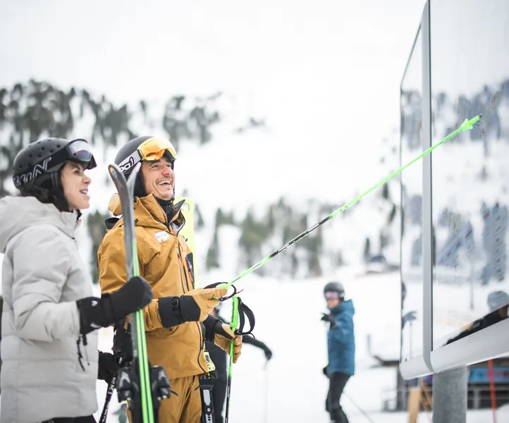 Zwei lachende Skifahrer studieren die Panoramatafel mit Pistenplan der Skiworld Ahrntal