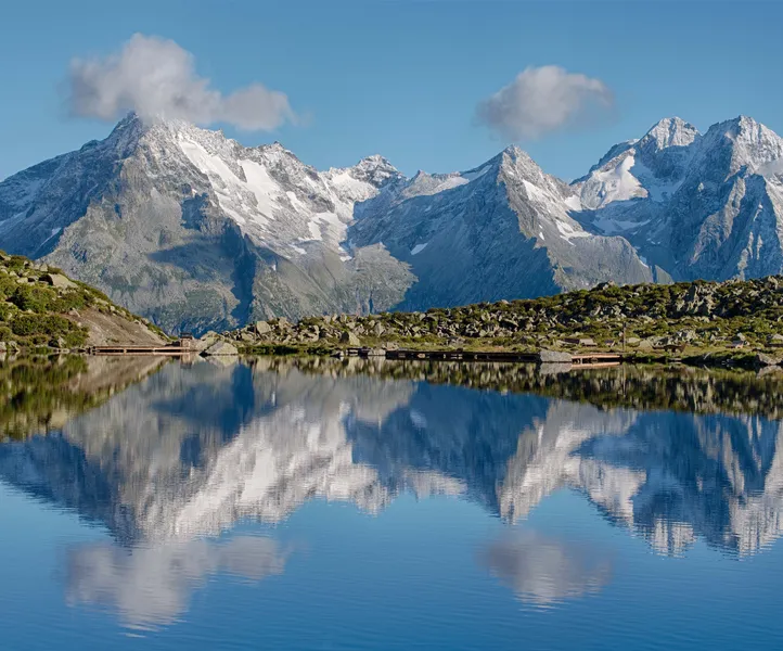 Hochgebirgsee spiegelt schneebedeckte Gipfel der Zillertaler Alpen