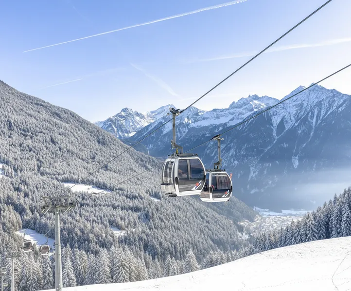 Gondeln der Kabinenbahn am Klausberg über verschneite Nadelwälder im Ahrntal