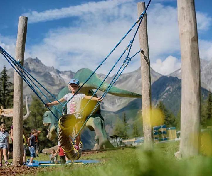 Mädchen schwingt auf Seilschaukel im Spielpark Klausberg mit Panorama der Zillertaler Alpen