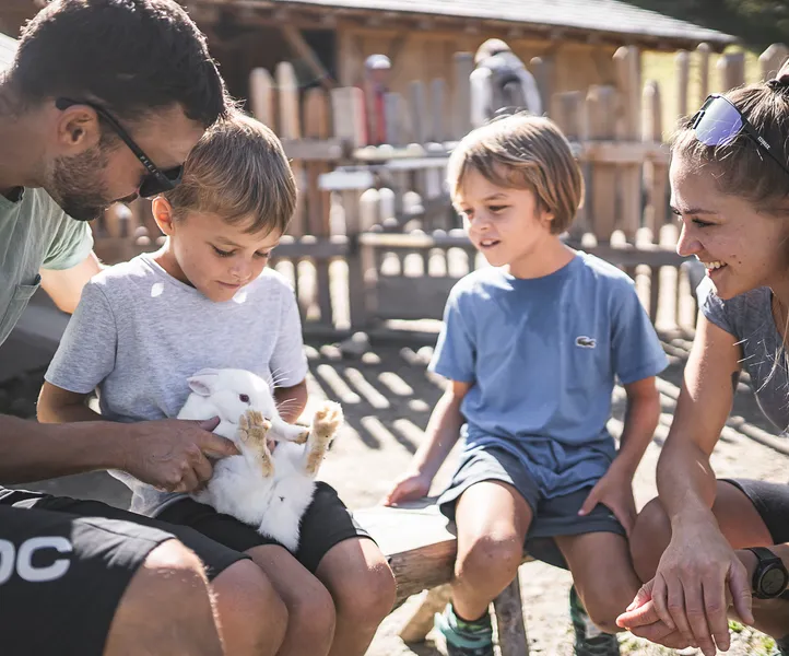 Kinder streicheln weißes Kaninchen am Streichelzoo im Familienpark Klausberg, Ahrntal Südtirol