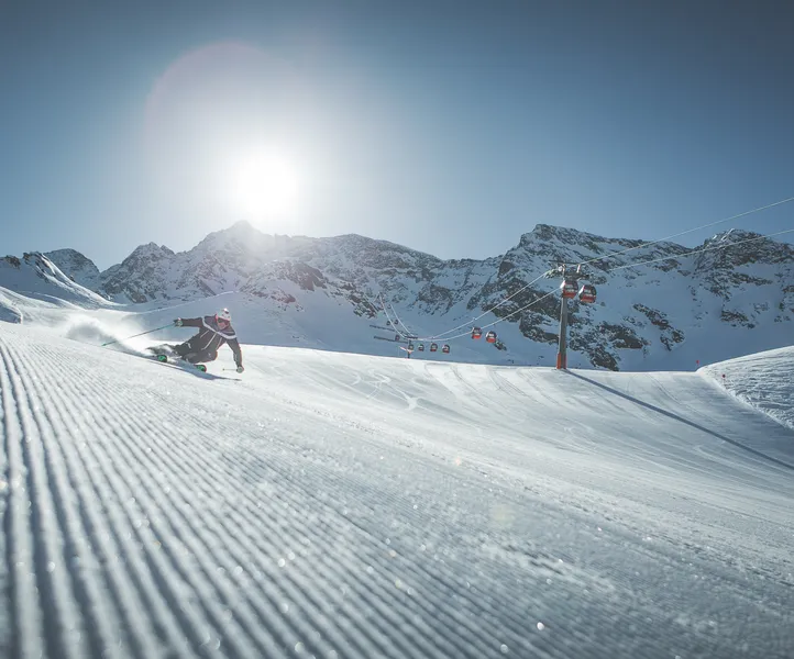Skifahrer beim Carvingschwung auf der Klausberg-Piste neben der Gondelbahn, sonniger Wintertag