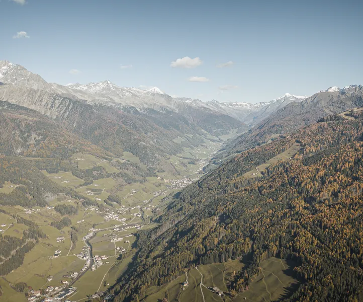 Drohnenaufnahme Ahrntal im Herbst mit goldenen Lärchenwäldern und Blick auf Zillertaler Alpen