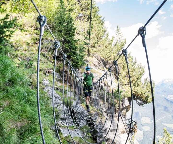 Kletterer überquert Hängebrücke am Klettersteig Speikboden im Sommer