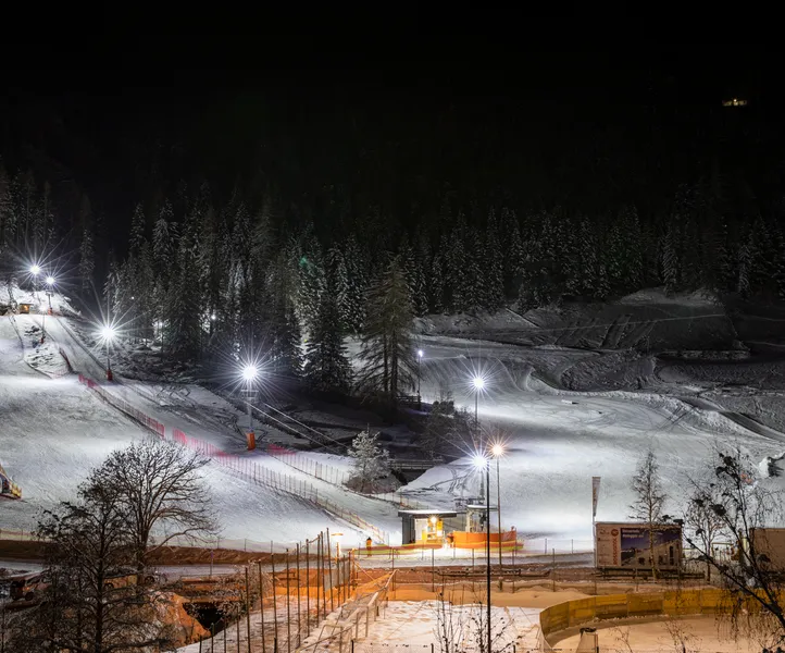 Beleuchtete Skipiste beim Nachtskilauf am Klausberg mit Skiverleih und verschneitem Nadelwald