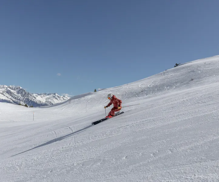 Female skier in red clothing on a freshly groomed slope at Klausberg with mountain panorama
