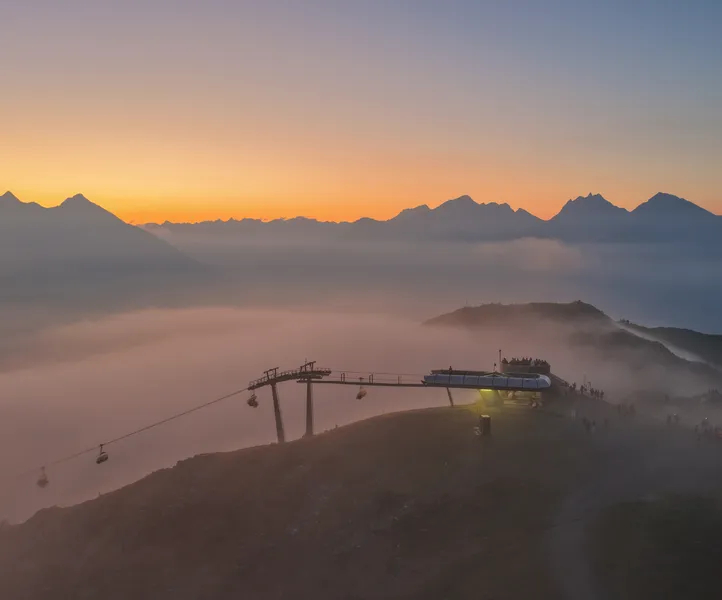 Gondeln der Kabinenbahn am Klausberg bei Sonnenuntergang mit Nebelmeer und Berggipfeln