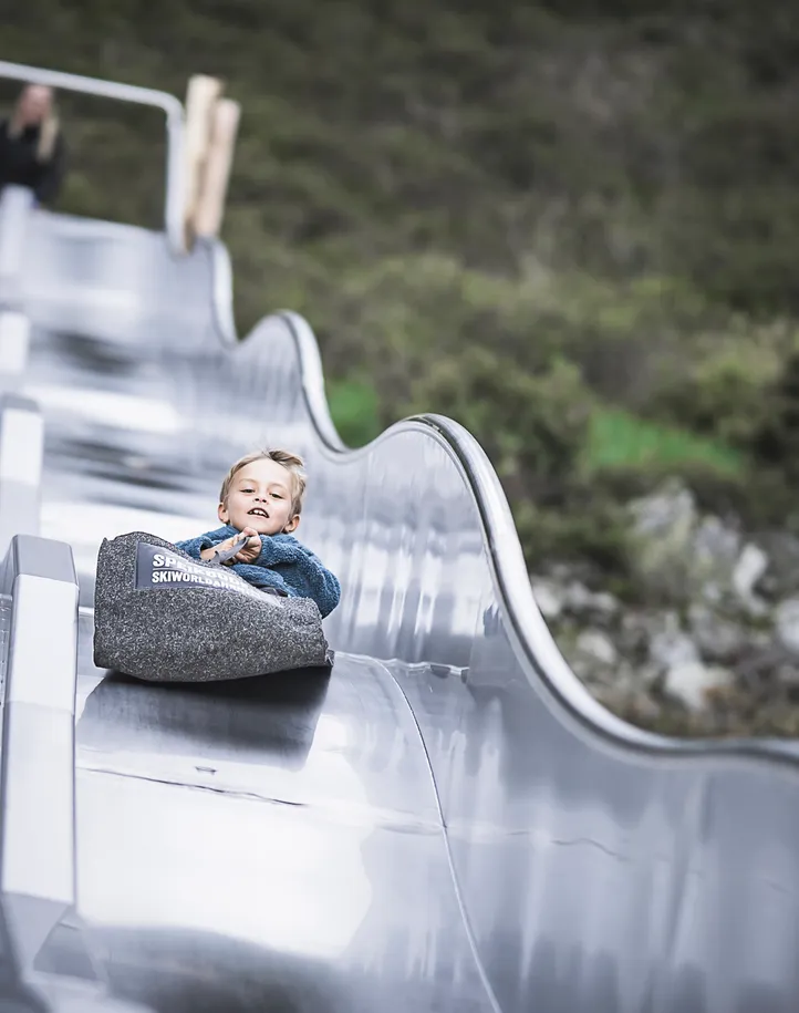 Kind rutscht lachend die Wellenrutsche am Speikboden Familienpark im Ahrntal hinunter