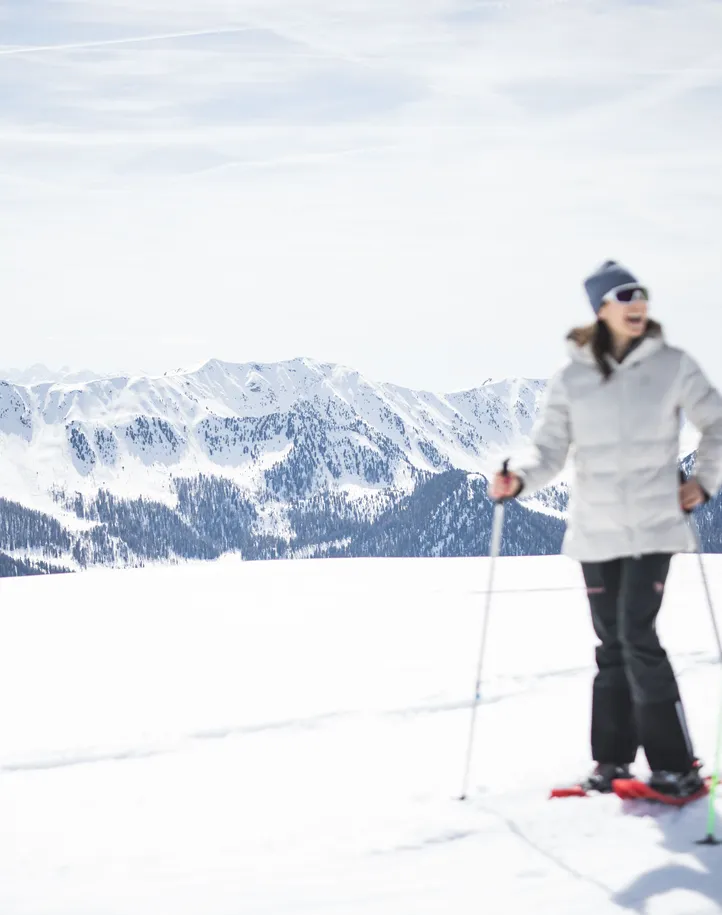 Paar beim Schneeschuhwandern auf sonniger Hochebene im Ahrntal mit Bergpanorama Südtirols