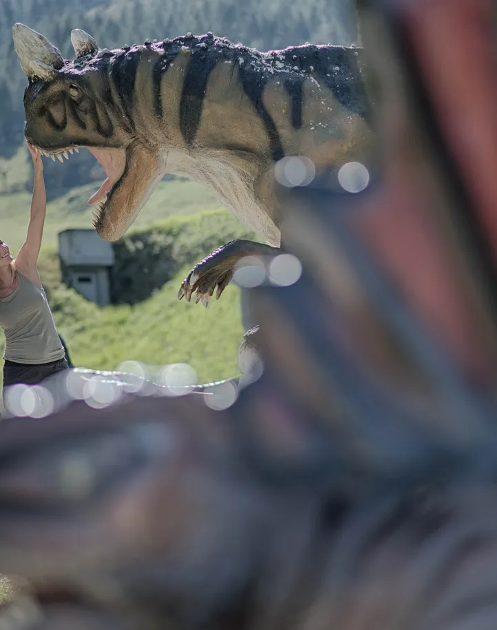 Familie mit Kind entdeckt lebensgroße Dinosaurier-Figur im Dinopark am Klausberg im Ahrntal