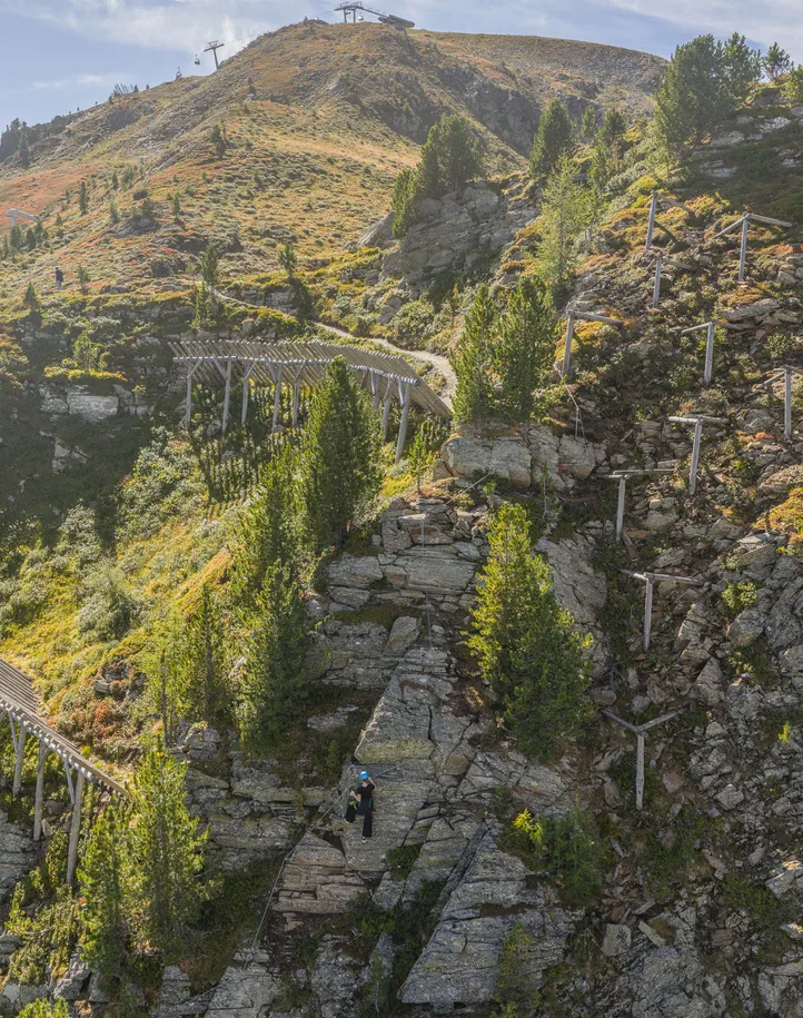 Panorama Klettersteig Ahrntal mit Kletterer, Seilbahn-Bergstation und herbstlicher Almlandschaft