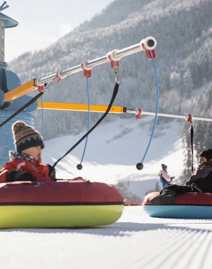 Children on colorful snow tubes on the tubing carousel in the kids' area in Ahrntal
