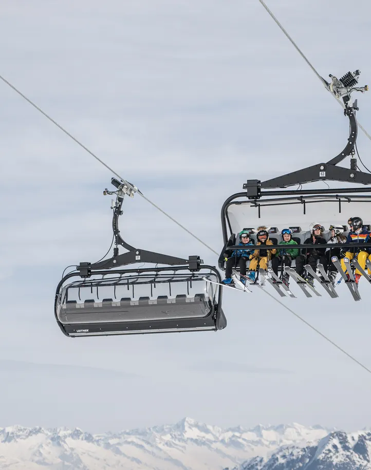 Zwei Sesselbahnen mit Skifahrern am Klausberg vor Bergpanorama im Winter