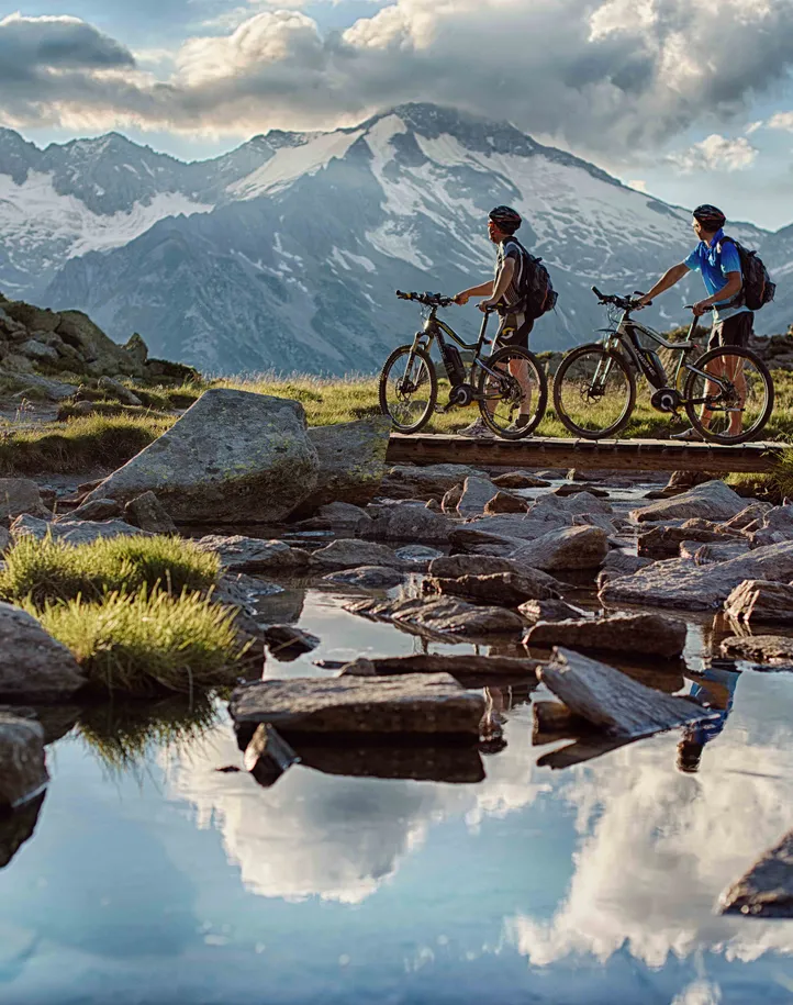 Zwei E-Mountainbiker vor dem Gletscherpanorama der Zillertaler Alpen auf einer Tour im Ahrntal