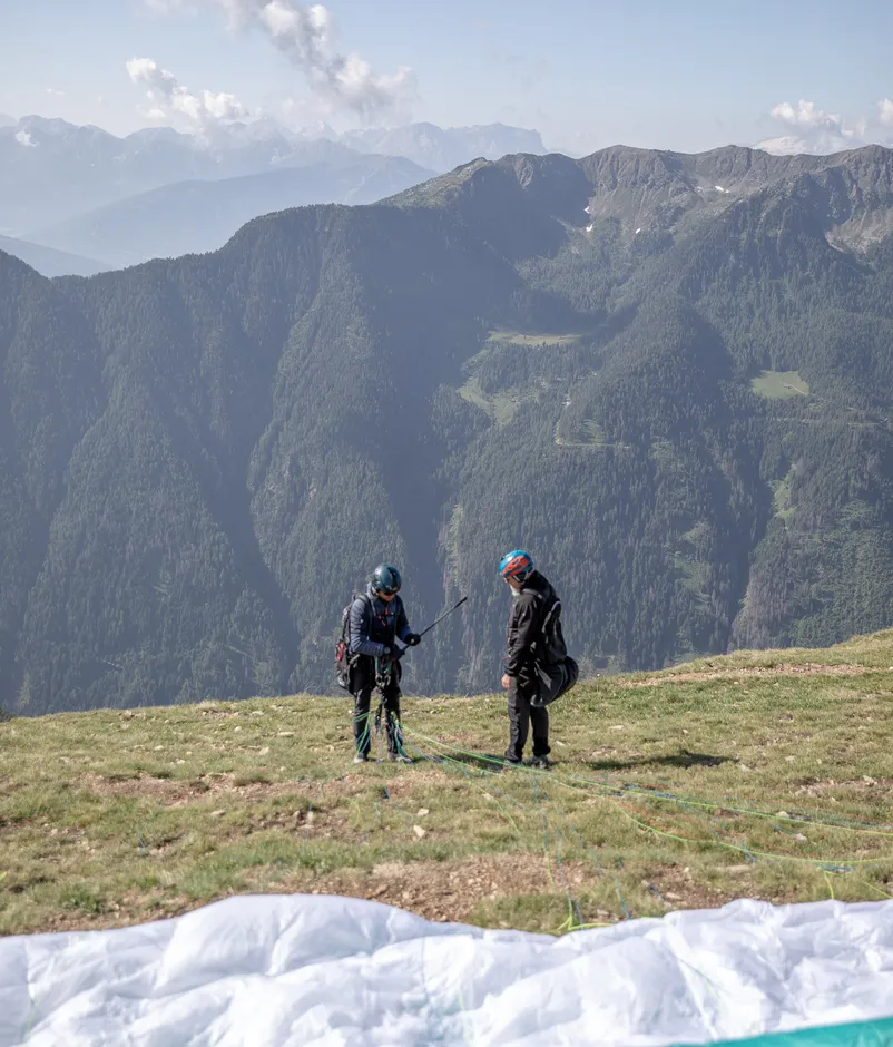 Paragleiter bereiten Gleitschirm am Startplatz auf Bergrücken im Ahrntal vor dem Flug vor