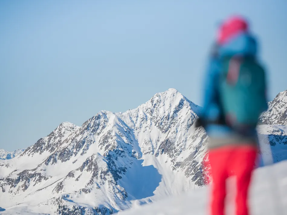 Skifahrer im Vordergrund mit scharfem Blick auf die schneebedeckten Gipfel am Klausberg und Speikboden