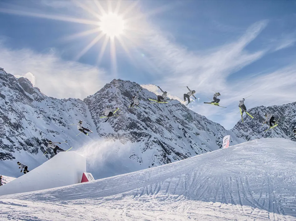 Freestyle skier performing a backflip in Klausberg Snowpark with Alpine mountain backdrop