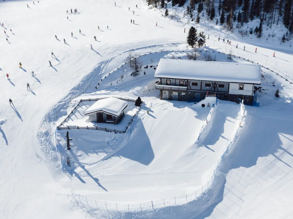Aerial view of the ski hut at Klausberg with skiers on the prepared winter slope