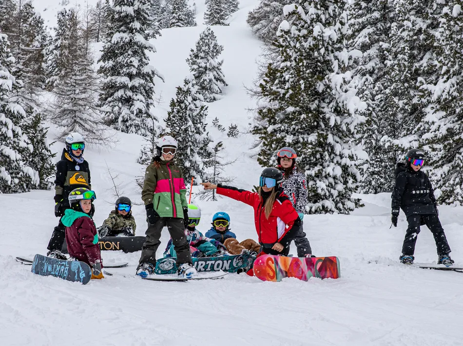 Kinder-Snowboardkurs mit Skilehrerin zwischen verschneiten Bäumen im Skigebiet Ahrntal