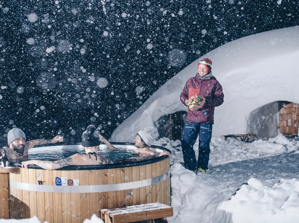 Relaxing in outdoor hot tub during snowfall – winter experience at the igloo village in Ahrntal