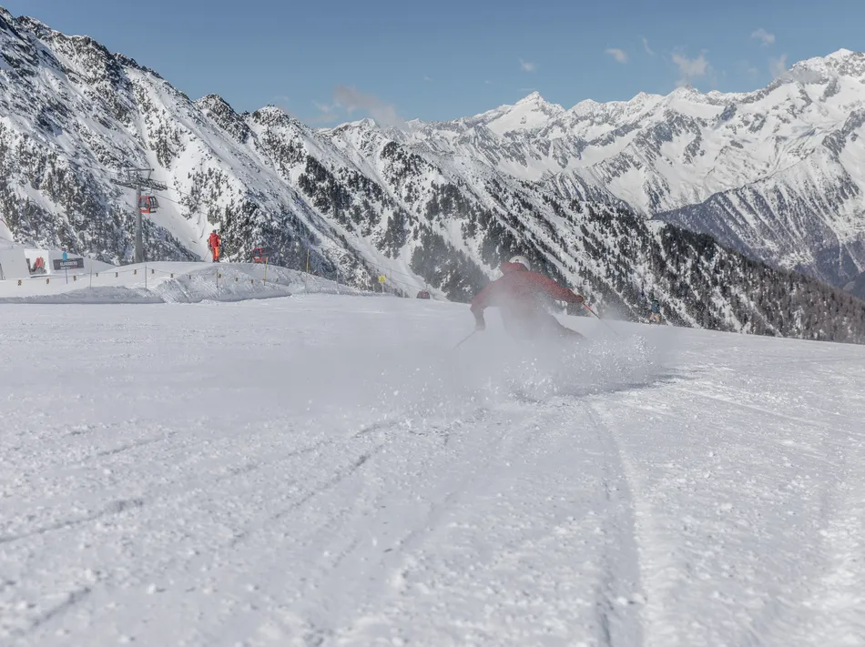 Skifahrer in roter Jacke auf präparierter Piste am Klausberg, Sessellift und Zillertaler Alpen