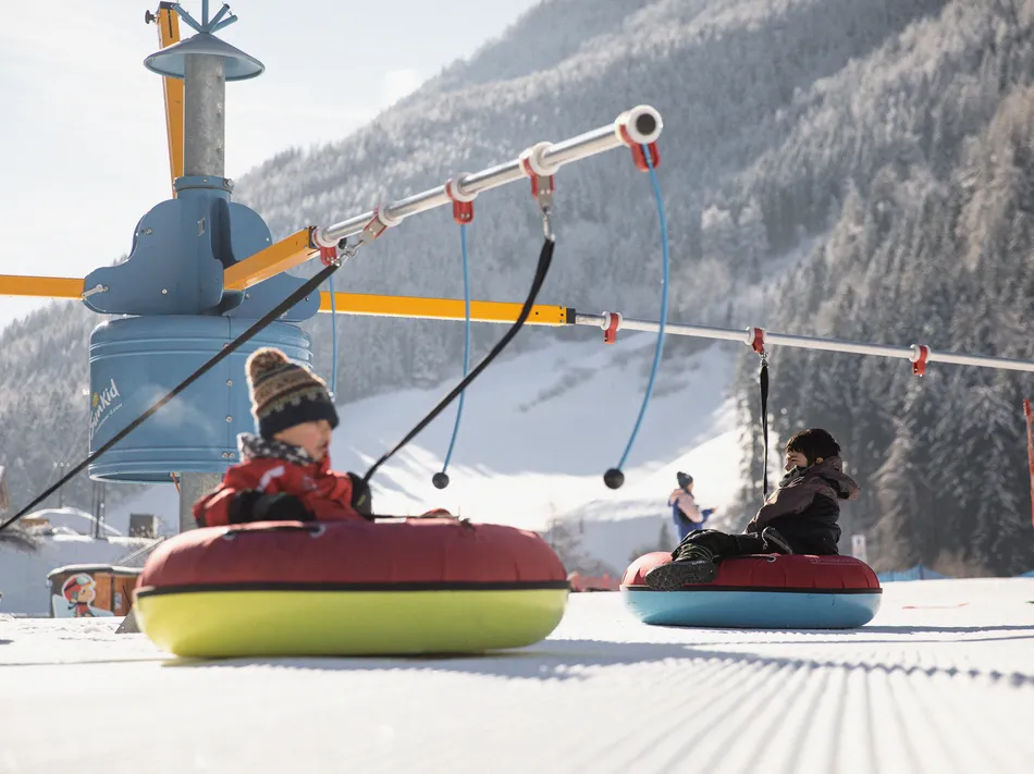 Kinder auf bunten Snowtubes am Snow-Tubing-Karussell im Kinderland des Ahrntals