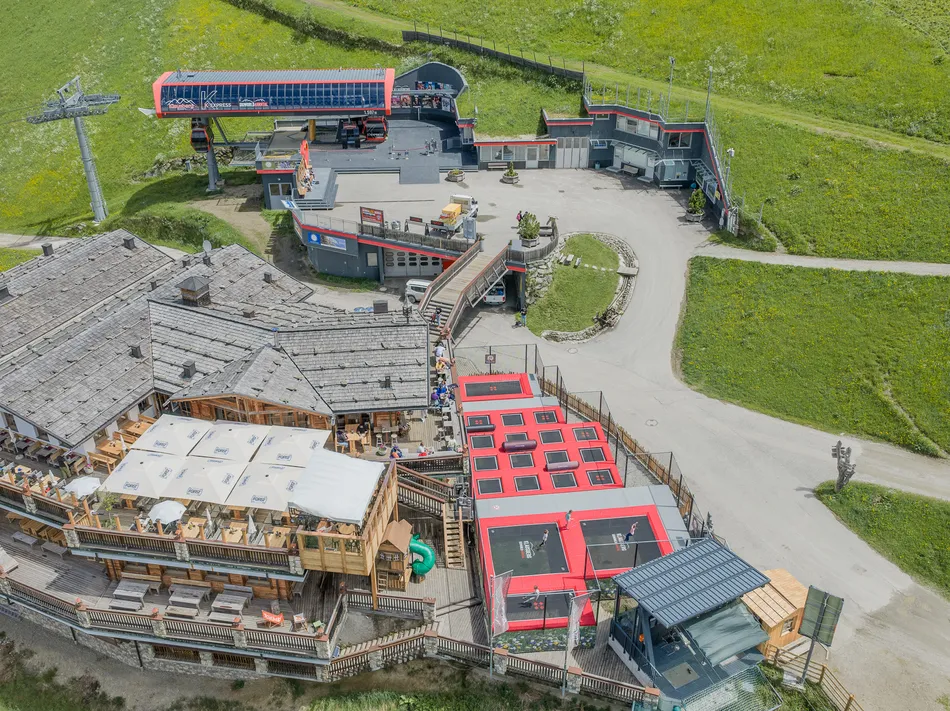 Bergstation des K-Express am Klausberg mit Almhütte, Sonnenterrasse und Trampolinpark im Sommer