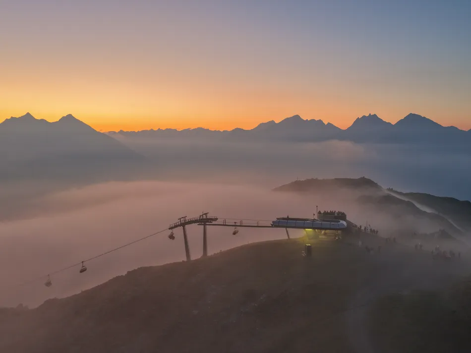 Cable car gondolas at Klausberg at sunset with sea of fog and alpine peaks