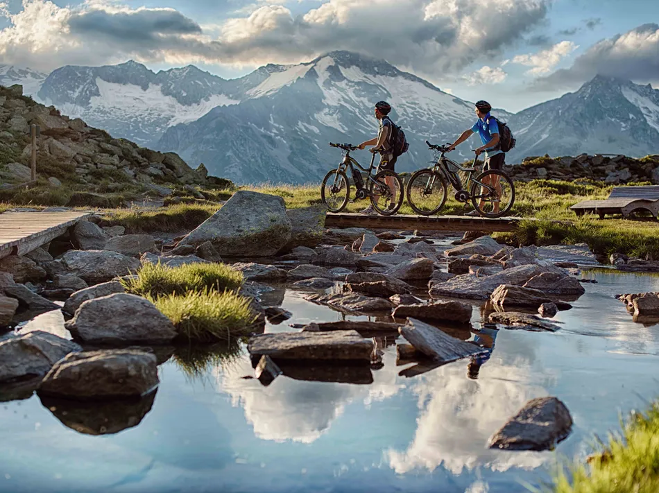 Zwei E-Mountainbiker vor dem Gletscherpanorama der Zillertaler Alpen auf einer Tour im Ahrntal