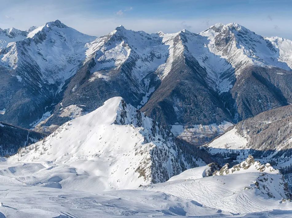 Wide panorama of the Zillertal Alps with ski tracks in deep snow and forested slopes in Ahrntal